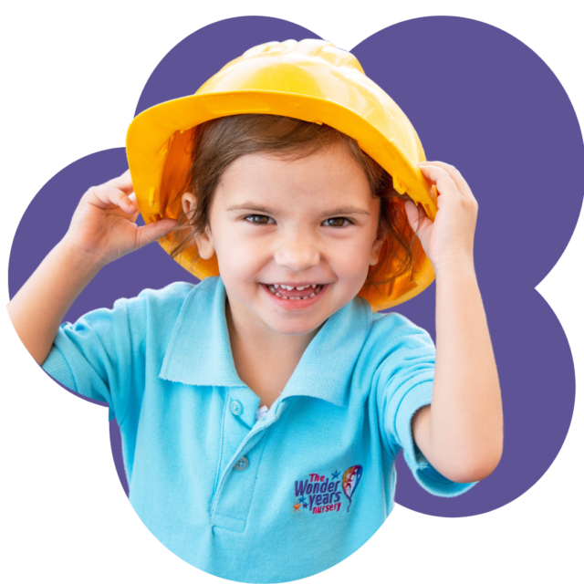 Happy child at The Wonder Years Nursery wearing a yellow hat – representing safe, nurturing class environments.